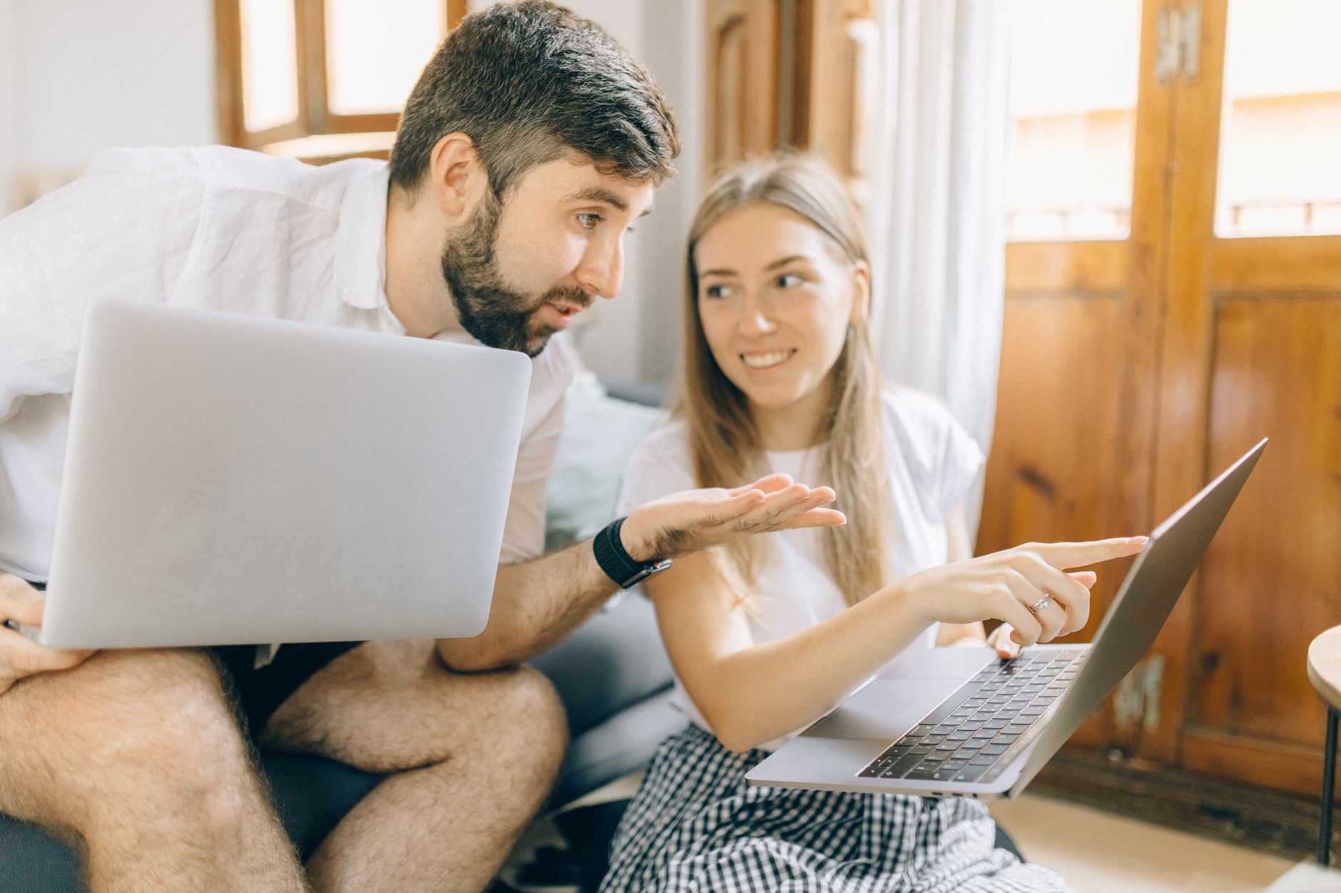 Een stel zit thuis naast elkaar met allebei een laptop en overlegt